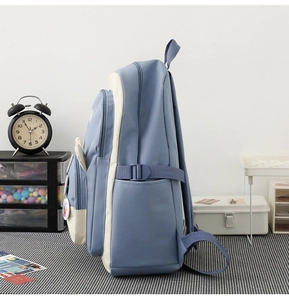 Side view of multi-compartment blue and white school backpack with buckle and badges