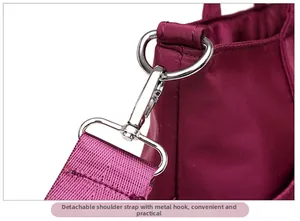 Detail of shiny silver metal hooks and detachable strap on purple nylon shoulder bag