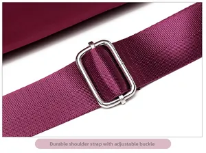 Detail of adjustable wine red nylon shoulder strap with silver metal buckle on a casual bag