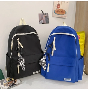 Détail de sacs à dos en nylon avec fermetures contrastées et pendentif à carreaux