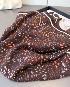 Detailed view of dark brown scarf showing herringbone texture and floral pattern