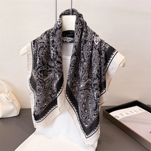 Elegant black and white paisley silk scarf displayed on a white mannequin torso