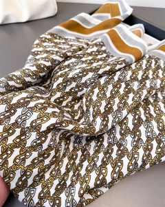 Detail of silk scarf showing vintage geometric chain patterns and striped border texture