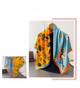 Detail of silk-like floral scarf with yellow leaf patterns and orange contrast borders