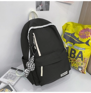 Détail d'un sac à dos en nylon avec liserés blancs et un pendentif à motif damier
