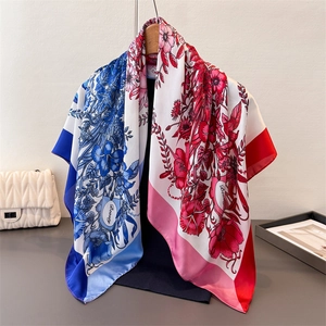 Detail of silk-like floral square scarf draped on a hanger with artistic prints