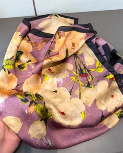Détail de l'imprimé floral sur un grand foulard en soie violette à bordure noire