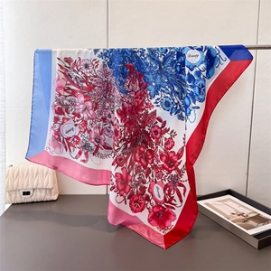 Artistic floral satin square scarf draped over a metal bar in a minimalist setting
