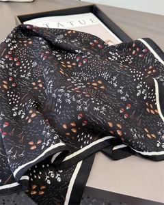 Detailed view of black herringbone silk scarf with botanical and shell print patterns