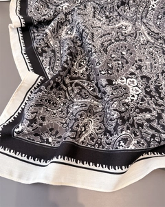 Detailed macro view of black and white paisley pattern scarf with elegant draped silk texture