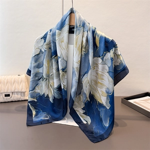 Détail d'un foulard en soie à fleurs bleu et or suspendu à un cintre en bois élégant