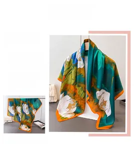 Detail of silk-like dark green scarf featuring white lotus prints and orange borders