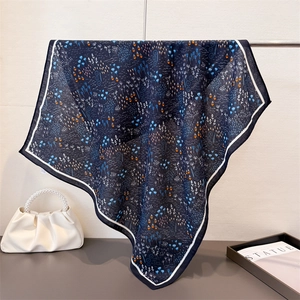 Detailed view of dark blue silk scarf with floral print hanging on a metal bar