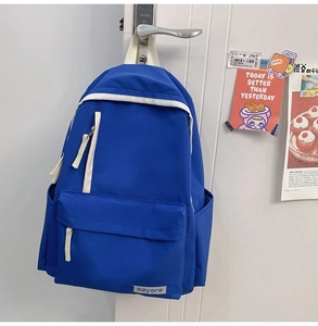 Détail d'un sac à dos en nylon bleu avec fermetures blanches et poches multiples