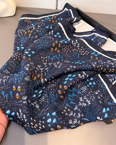 Detail of blue floral cotton-linen feel scarf with contrast white border and soft texture