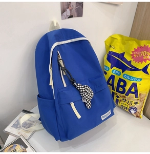 Détail d'un sac à dos en nylon bleu avec étiquette tissée bayore et breloque en damier
