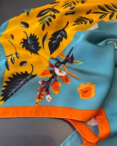 Detail of silk satin scarf showing vibrant yellow and cyan prints with orange floral patterns
