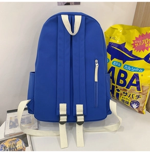 Détail d'un sac à dos en nylon bleu avec bretelles blanches et poches latérales fonctionnelles