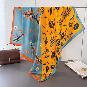 Silky square scarf with yellow and blue color-block leaf and floral print on metal stand