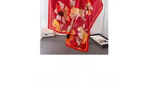 Detailed view of red floral silk-like scarf draped elegantly with fashion accessories
