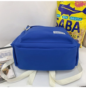 Vue détaillée du sac à dos en nylon bleu Klein montrant les sangles blanches épaisses