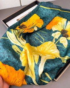 Detail of silk satin scarf with yellow floral print on deep dark green background