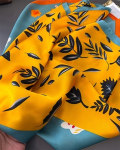 Detail of silk-like scarf featuring bold leaf prints and vibrant color-blocking patterns