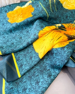 Detailed texture of teal silk scarf with large yellow floral prints and fine rolled edges