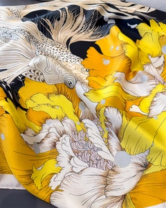 Detail of silk scarf showing yellow floral patterns and white koi fish print on fabric