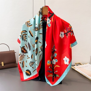 Detail view of red and blue floral print silk scarf with fine stitching and satin texture