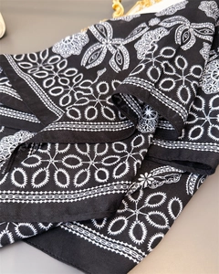 Detailed view of white ethnic floral embroidery on a black cotton-linen feel square scarf