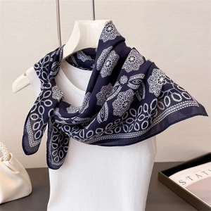 Elegant navy blue silk scarf with white floral geometric pattern on a mannequin model
