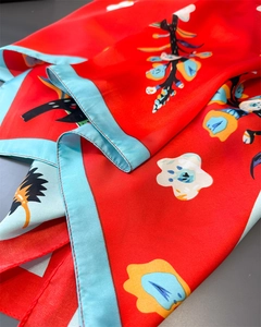 Detailed view of red floral silk scarf with light blue hem and smooth texture
