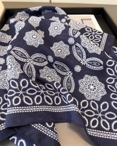 Close-up of navy blue scarf featuring white lace floral patterns and twill texture