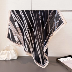 Detail eines Vintage-Seidenschals mit Reitsportmuster, Gürteln und Ketten in Schwarz-Beige