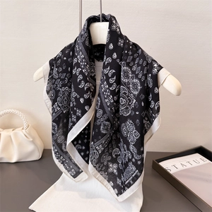 Sciarpa classica con stampa paisley bianca e nera su supporto minimalista con accessori eleganti