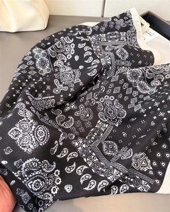 Vista dettagliata di una sciarpa in cotone e lino con motivo paisley e bordo a contrasto
