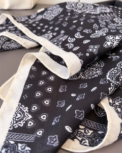 Dettaglio di sciarpa paisley nera con bordo crema che mostra la fine trama twill