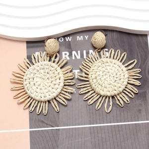 Detail of handmade raffia sunflower earrings with woven petals in bohemian style