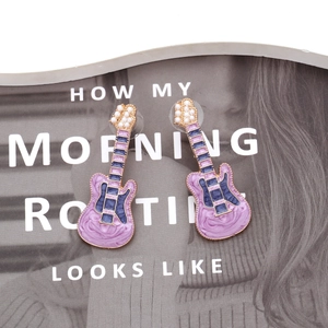 Detail of purple and blue enamel guitar earrings with white pearl and gold metal trim
