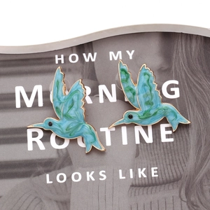 Enamel hummingbird stud earrings with blue-green marble texture on fashion magazine cover