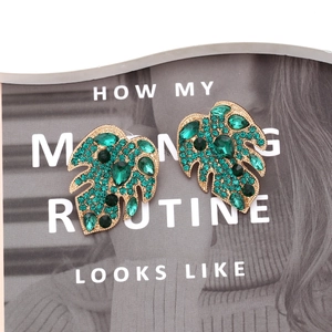 Detail of leaf earrings featuring green rhinestones and faux pearls on gold alloy base