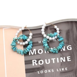 Double hoop earrings with turquoise stones and white pearls on a fashion magazine