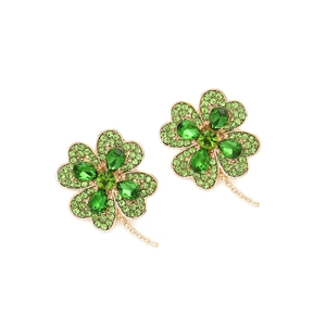 Détail macro de boucles d'oreilles trèfle en alliage doré avec cristaux et diamants verts
