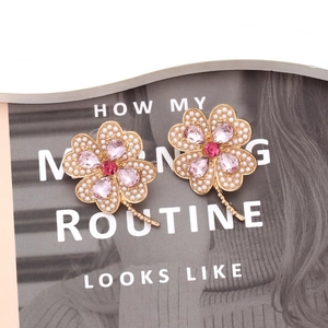 Détail des boucles d'oreilles trèfle avec cristaux roses et perles sur magazine