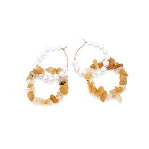 Detail of double-layer hoop earrings featuring white pearls and natural yellow stone beads