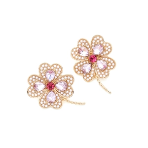 Détail de boucles d'oreilles fleur à quatre pétales avec strass roses et perles