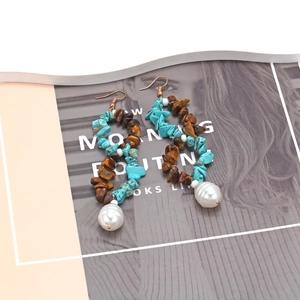 Bohemian turquoise and tiger eye beaded drop earrings with large pearls on magazine background