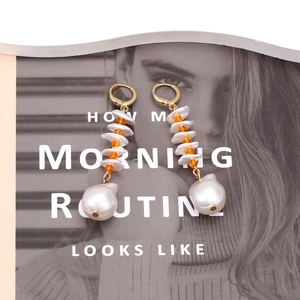Boucles d'oreilles de luxe avec cristaux orange et perles baroques sur magazine