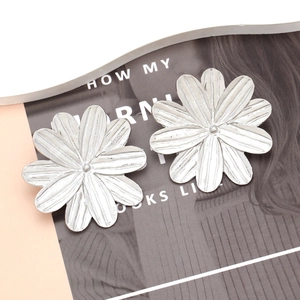 Detail of silver floral earrings with fine vertical brushed texture and metallic petals